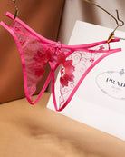 Rose pink mesh crotchless thong with black lace trim and red floral embroidery