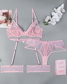 Pink lingerie set flat lay: lace half-cup bra, garter belt, panties, and stockings.