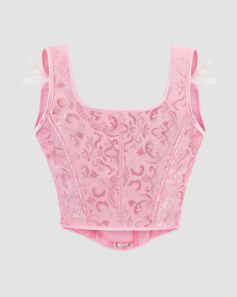 Pink corset top with floral jacquard fabric, structured seams, and ribbon bows at straps