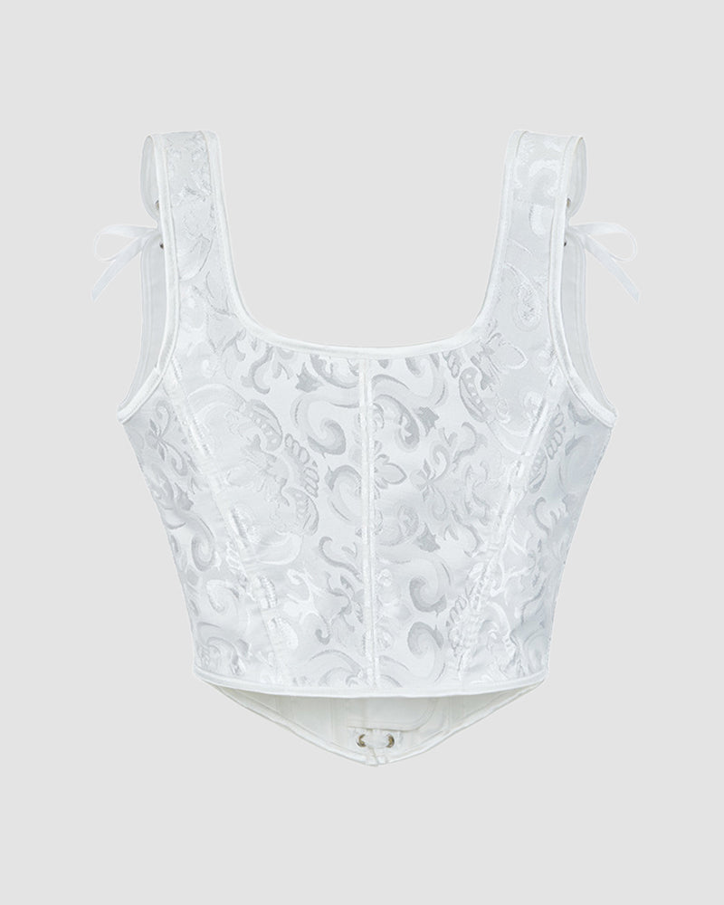 White corset top with floral jacquard pattern, structured boning, and ribbon bows at straps
