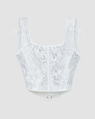 White corset top with floral jacquard pattern, structured boning, and ribbon bows at straps