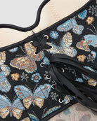Black butterfly-pattern corset close-up with metal eyelets and black lace-up ties