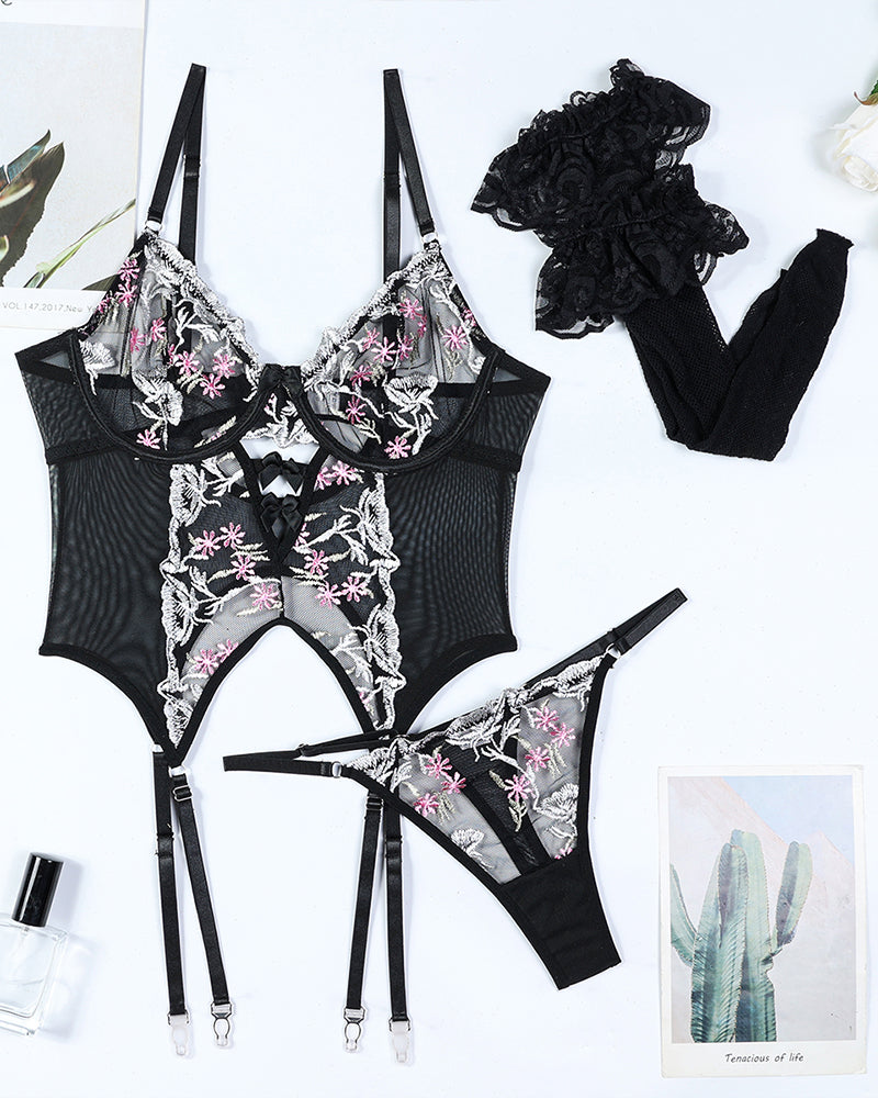 Black floral-embroidered lingerie set flat lay with bra, bodysuit, thong, and garters
