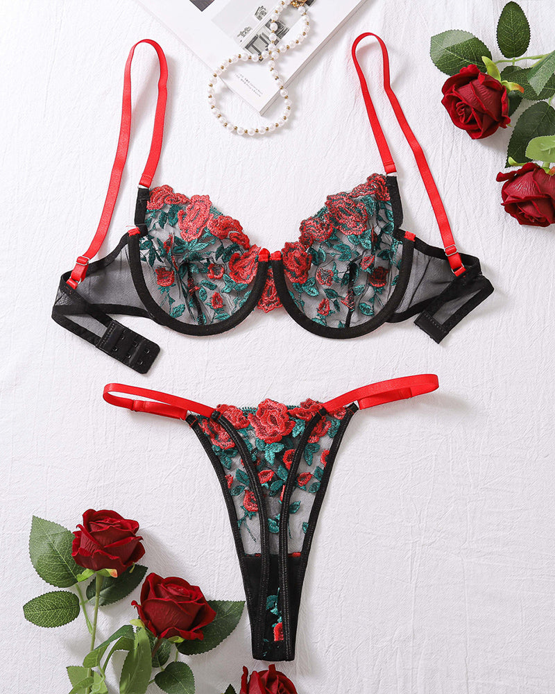 Flat lay of sheer bra and thong set in black with red straps and floral embroidery