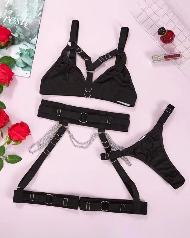 Black metal chain strap bra set flat lay: bra, thong, thigh straps, and waist harness