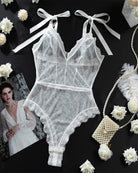 White sheer lace mini bodysuit flat lay with bow straps and scalloped lace edges
