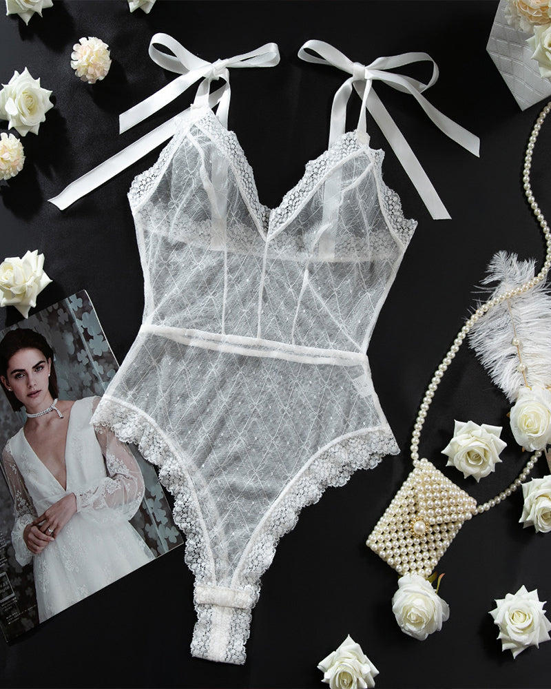 White sheer lace mini bodysuit flat lay with bow straps and scalloped lace edges