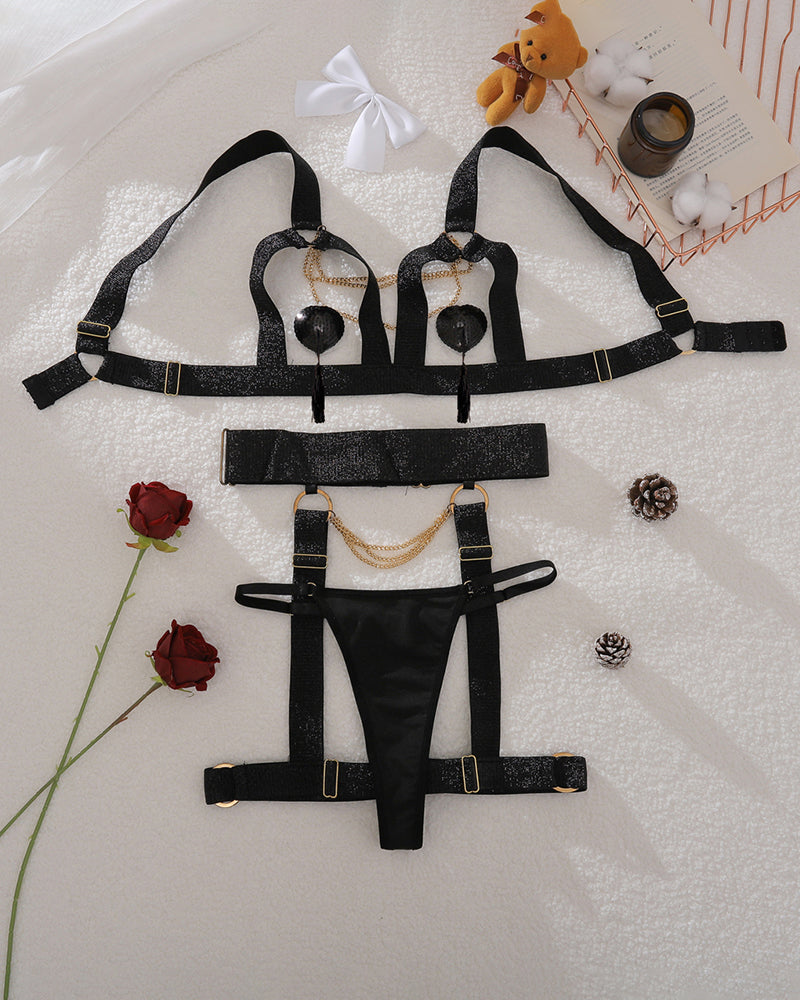 Black bra, panty, and garter set with chain details laid out on fabric