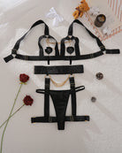 Black bra, panty, and garter set with chain details laid out on fabric