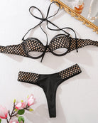 Black halter underwire bra and thong panty set, laid out with fishnet trim
