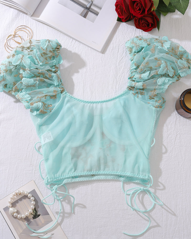 Light green embroidered bralette top with scalloped trim and lace-up ties, flat lay