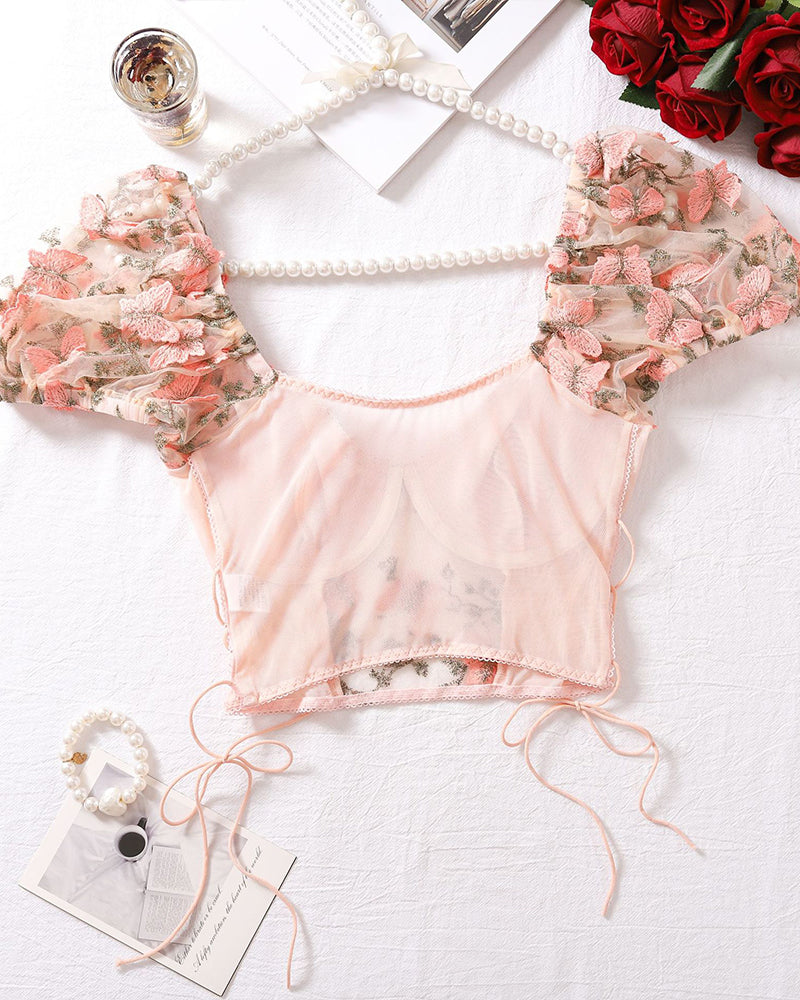Pink sheer embroidered bralette top with lace-up sides and ruffled floral sleeves, flat lay