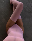 Pink sheer bodysuit with matching thigh-high stockings, pulled over legs