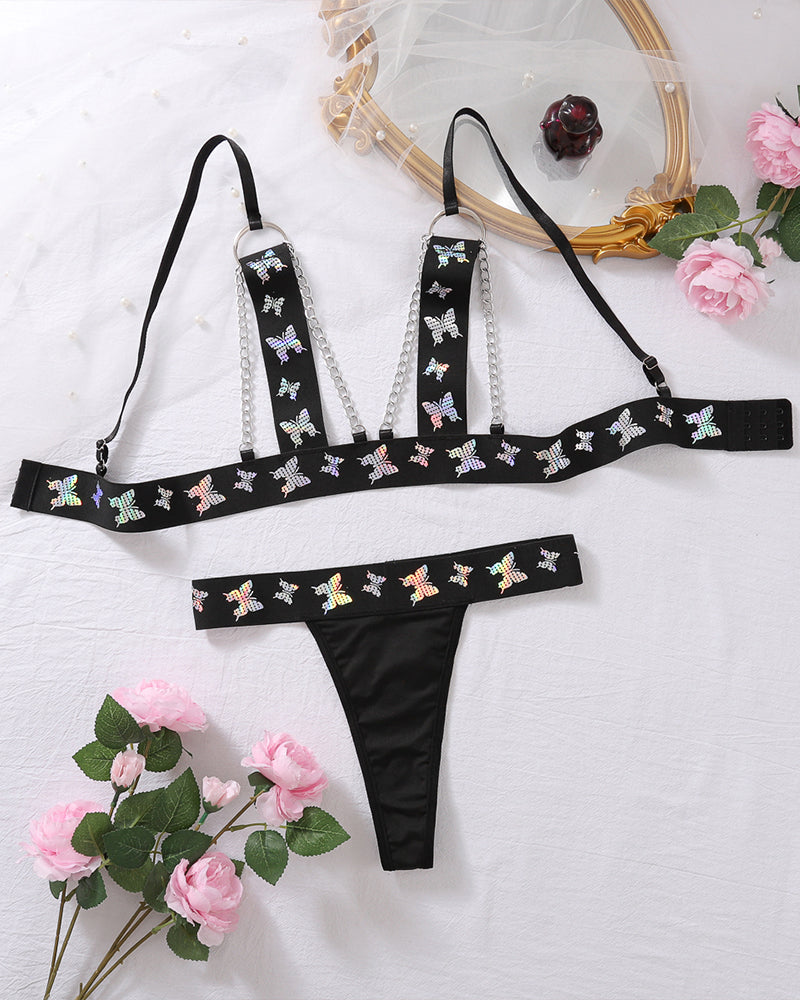 Black butterfly print lingerie set: chain-strap bra top and matching thong, flat lay