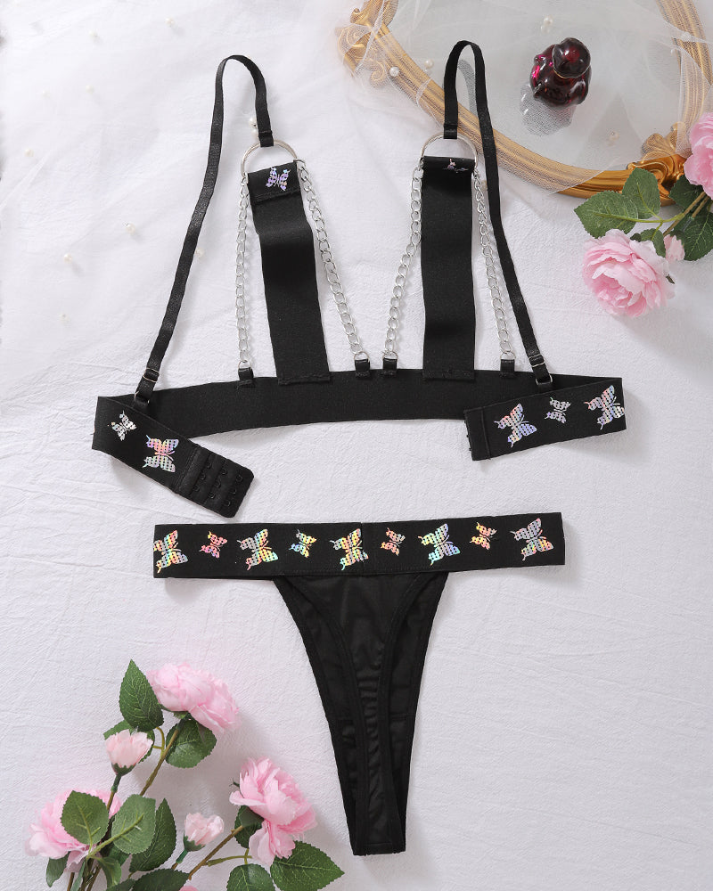 Black butterfly print lingerie set with chain-strap bra and thong, flat lay