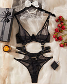 Black sheer mesh bodysuit laid flat, strappy harness style with adjustable straps
