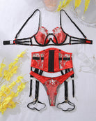 Red embroidered lingerie set laid flat: bra, corset belt, thong with garters