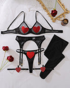 Black sheer mesh bra, heart appliqué panty, garters, and thigh-high stockings laid out