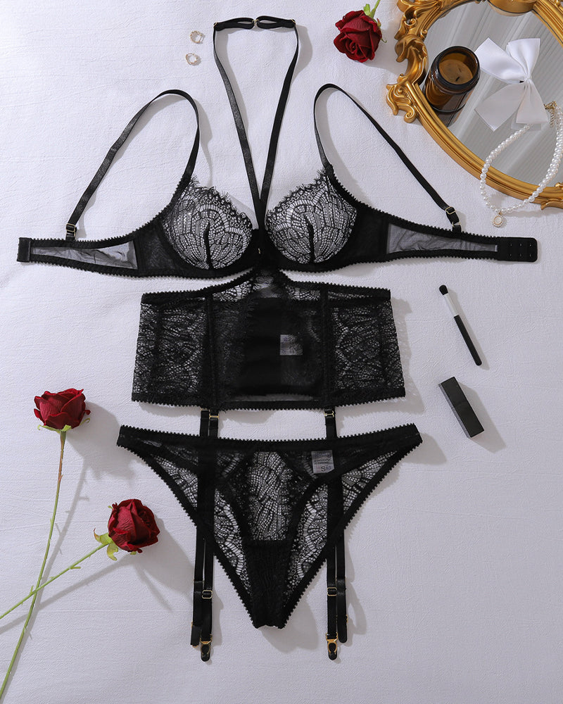 Black eyelash lace lingerie set laid out: bra, garter belt, thong, and straps