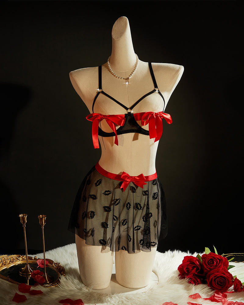 Black bra and kiss-print tulle mini skirt on mannequin, with red bow details
