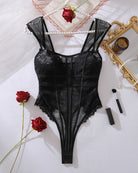 Black lace bodysuit laid flat with spaghetti straps, sheer mesh center and lace edges