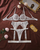 White sheer lace lingerie set flat lay: underwire bra, garter belt, and thong