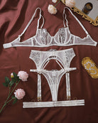 White lace lingerie set flat lay with underwire bra, garter belt, and high-cut panties