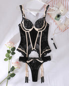 Black lace corset bodysuit with ivory trim, matching garter straps, and thong bottom