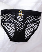 Black fishnet cutout panties laid flat, with gold heart-ring center detail