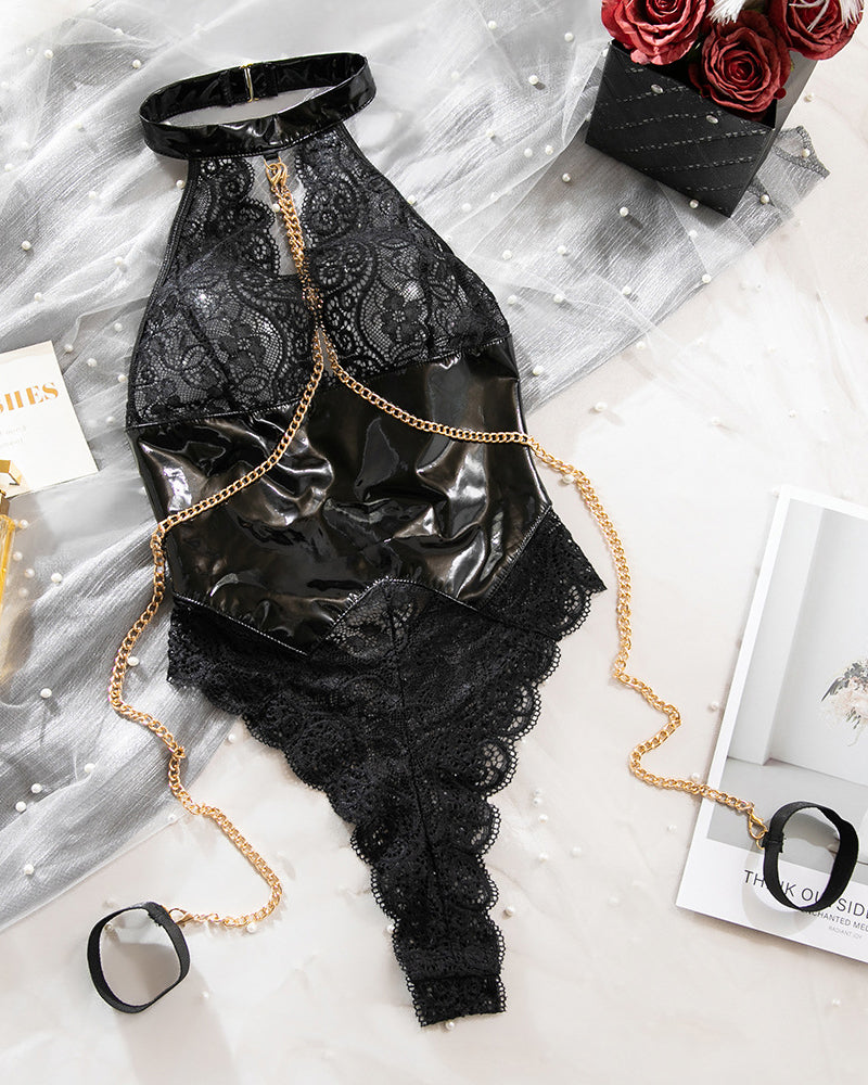 Black lace and vinyl-look halter bodysuit laid flat with gold chain accessories