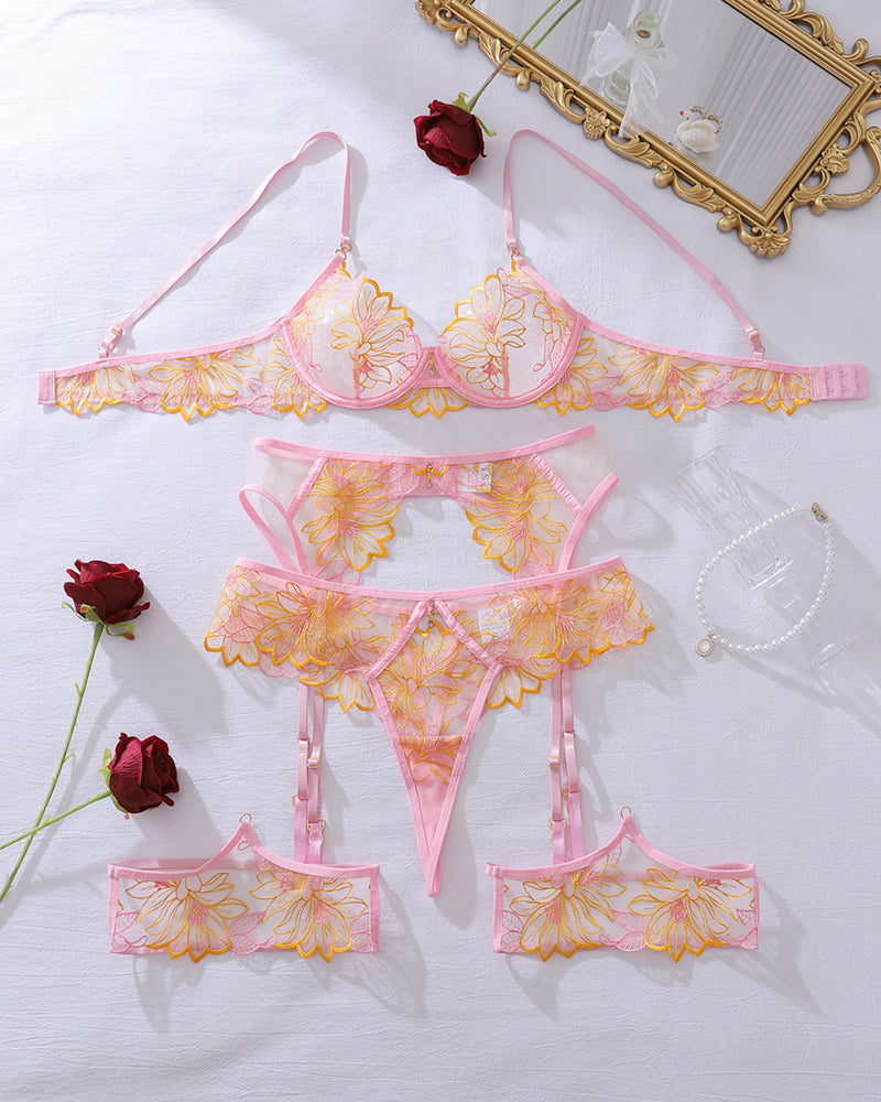 Flat lay of pink floral sheer mesh lingerie set: bra, garter belt, thong