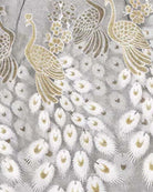 Embroidered peacock feather pattern fabric with gold and white thread details