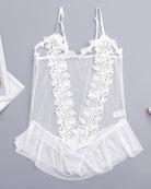 White sheer lace bodysuit with floral appliques and ruffle hem, laid flat