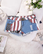 High-waisted denim shorts with American flag patch design, distressed cut and frayed hem
