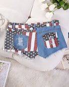 High-waisted denim shorts with flag-themed patchwork pockets and frayed distressed hem