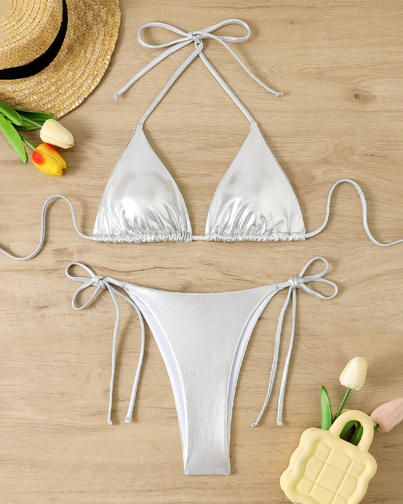 Shiny silver metallic triangle halter bikini set with side-tie bottoms, laid flat
