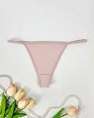 Seamless low-rise thong panties in light pink, smooth minimal-coverage design.