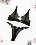 Black sheer mesh bra and panty set with O-ring accents, flat lay