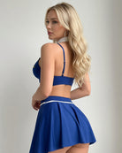 Dark blue lingerie set with racerback bra straps and pleated skirt, white waistband trim