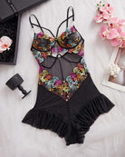 Black floral lace bodysuit on white, adjustable straps and ruched ruffle hem