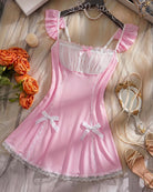 Pink satin babydoll mini dress with puff sleeves, ribbon bow front, and lace hem