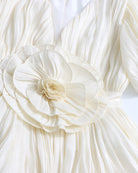 Close-up: champagne floral waist rosette on a pleated mini dress with puff sleeves