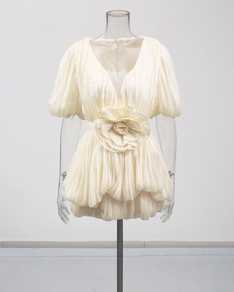 Champagne pleated mini dress with deep V, puff sleeves, and floral waist rosette