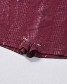 Burgundy croc-embossed faux leather romper bodysuit, close-up of shorts hem