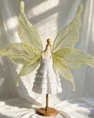 Yellow-green glitter fairy wings with leaf-shaped design over a white ruffle costume