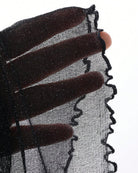Black glitter sheer fabric close-up with scalloped edge trim
