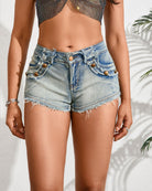 Light blue low-rise distressed denim hot shorts with distressed seams and rivet pockets