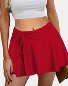 Red pleated high-waist drawstring skirt with tied waist cords and flared hem.